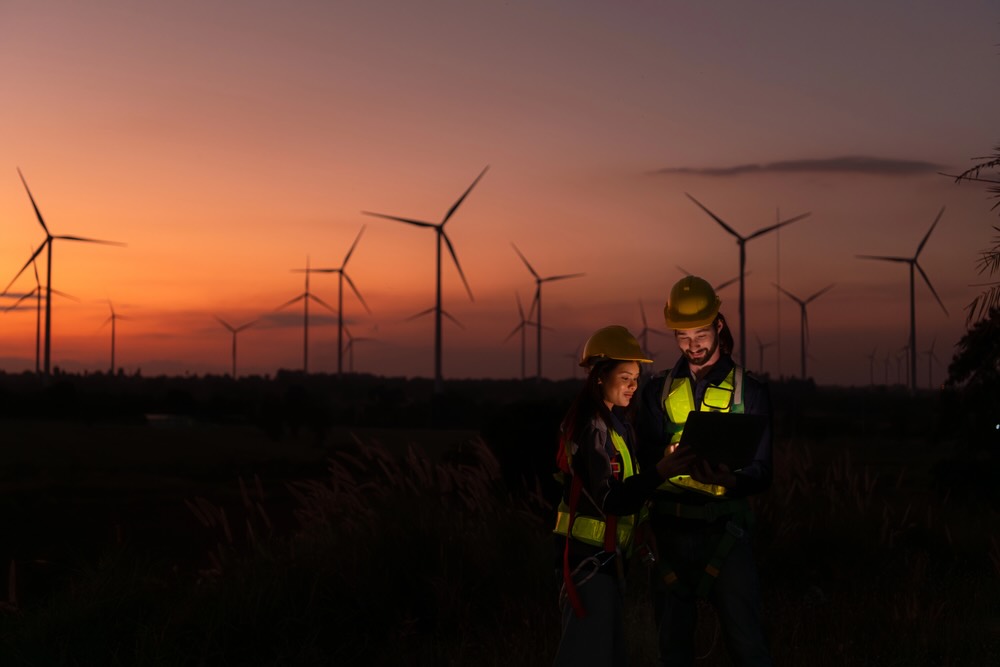 Engineers working on wind turbines farm at sunset, Wind turbines are alternative energy source.